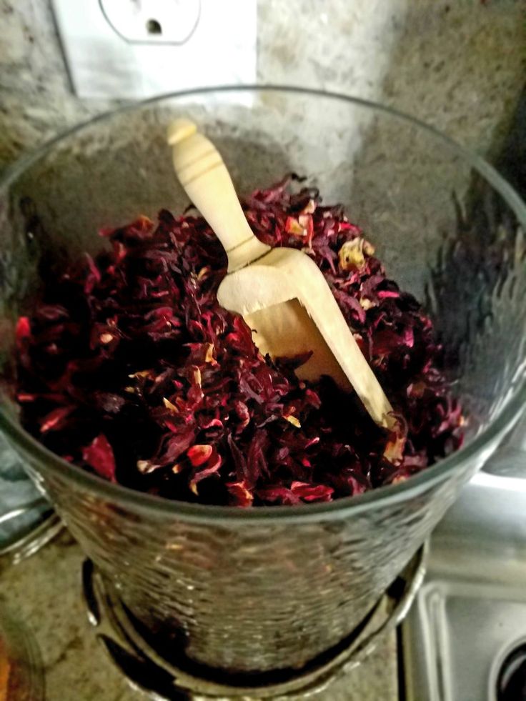 a glass bowl filled with red flowers on top of a stove burner next to a wooden spatula