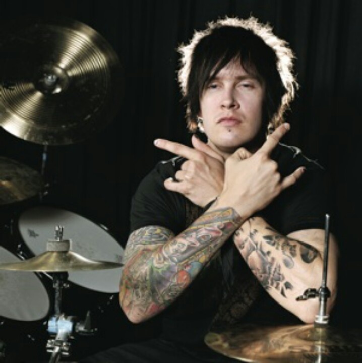 a man with tattoos sitting in front of a drum set