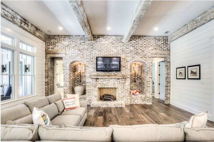 a living room with couches and a tv on the wall in front of a fireplace