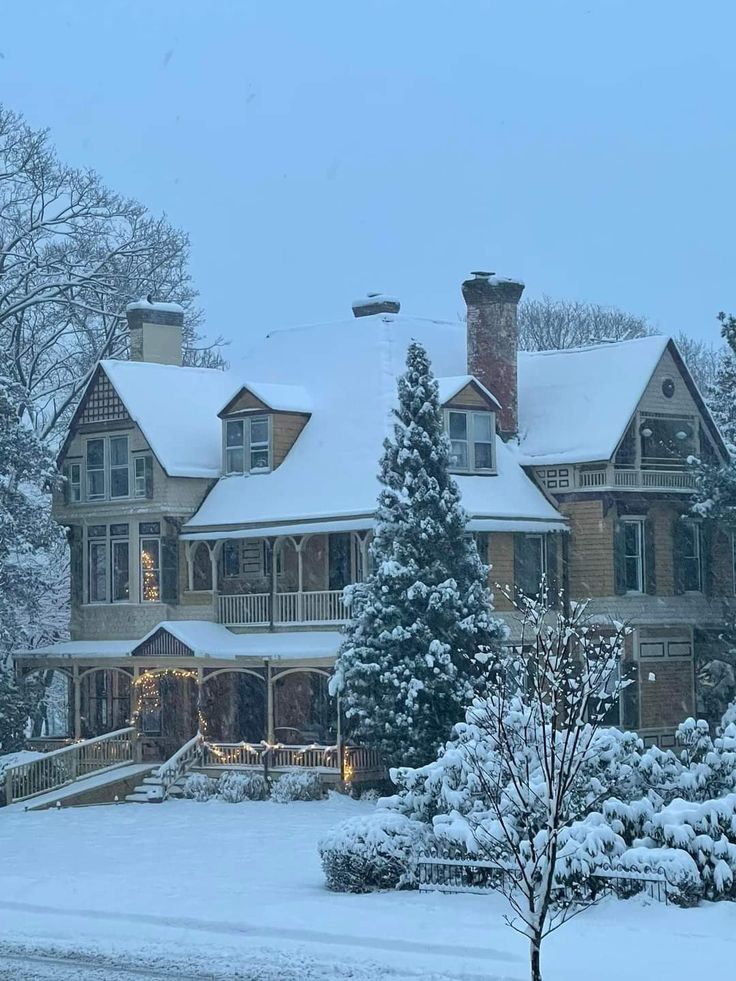 a large house covered in snow next to trees