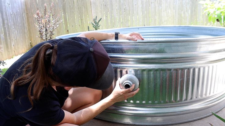 a woman in black shirt and hat working on a metal container with an air blower