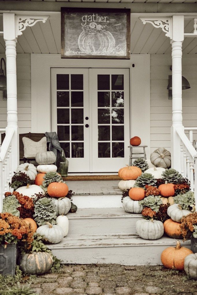 the front porch is decorated with pumpkins and gourds