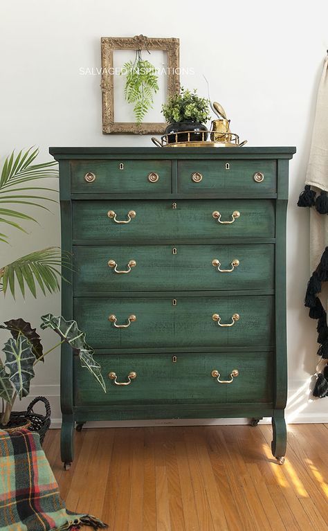 a green chest of drawers in a room with wooden floors and plants on the wall