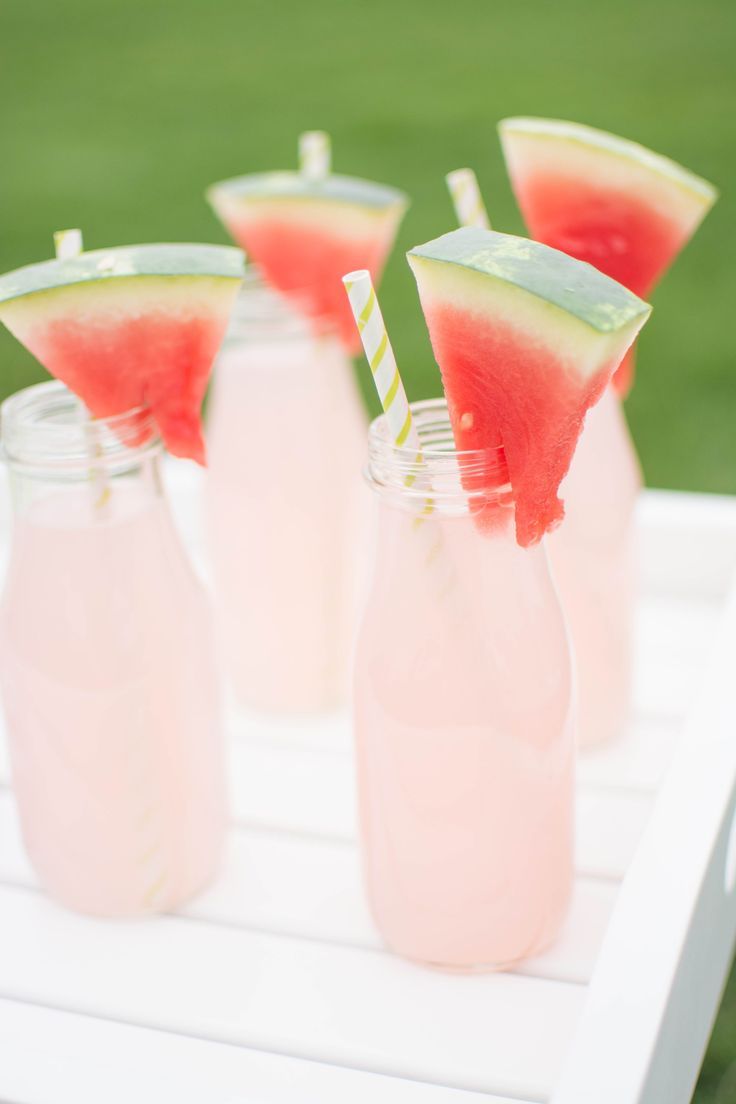 four watermelon drink in mason jars with straws on the top and one has a slice of watermelon