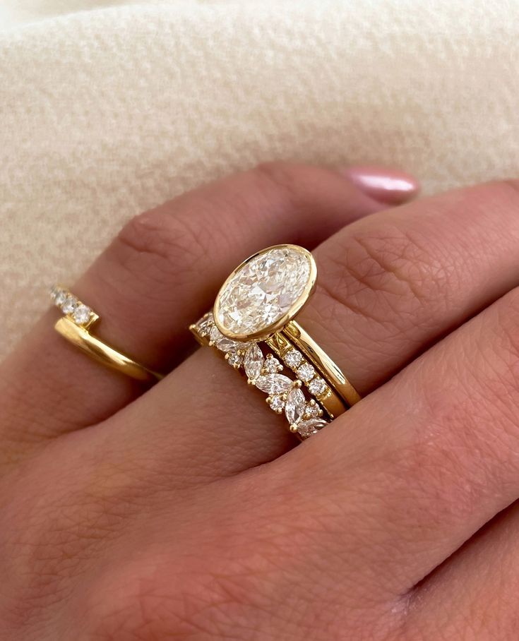 a woman's hand with two gold rings and one diamond ring on her finger