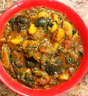 a red bowl filled with stew on top of a counter next to a knife and fork