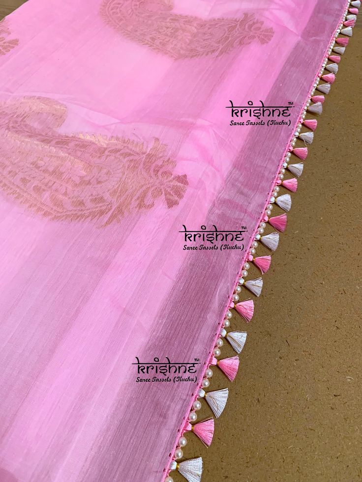 pink and white sari with tassels on the border, in front of a tan