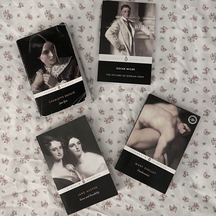 three books are laying on a bed with floral print sheets and white sheet coverings