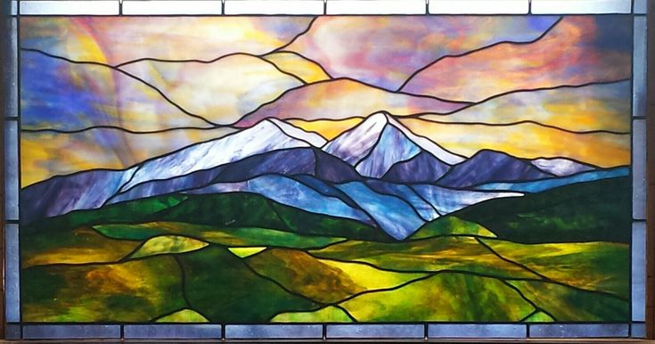 a stained glass window with mountains in the background