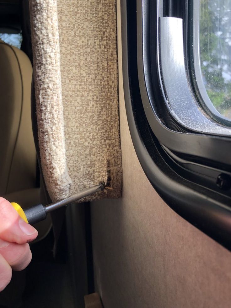 a person holding a screwdriver in their hand near the window of a vehicle