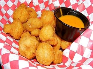 some fried food on a red and white checkered table cloth next to a bowl of soup