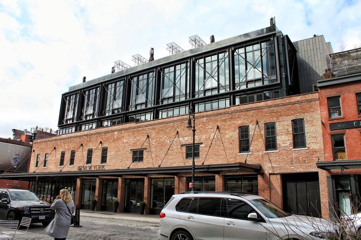 a woman walking down the street in front of an old brick building with many windows