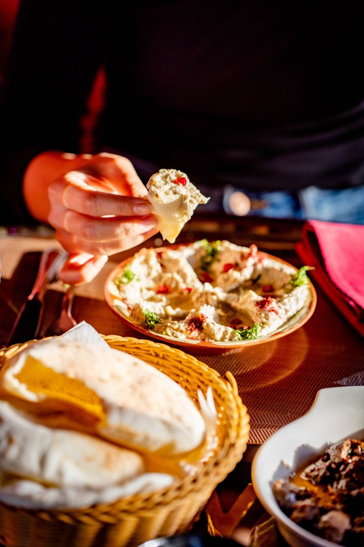 a person eating food at a table with other plates and bowls in front of them