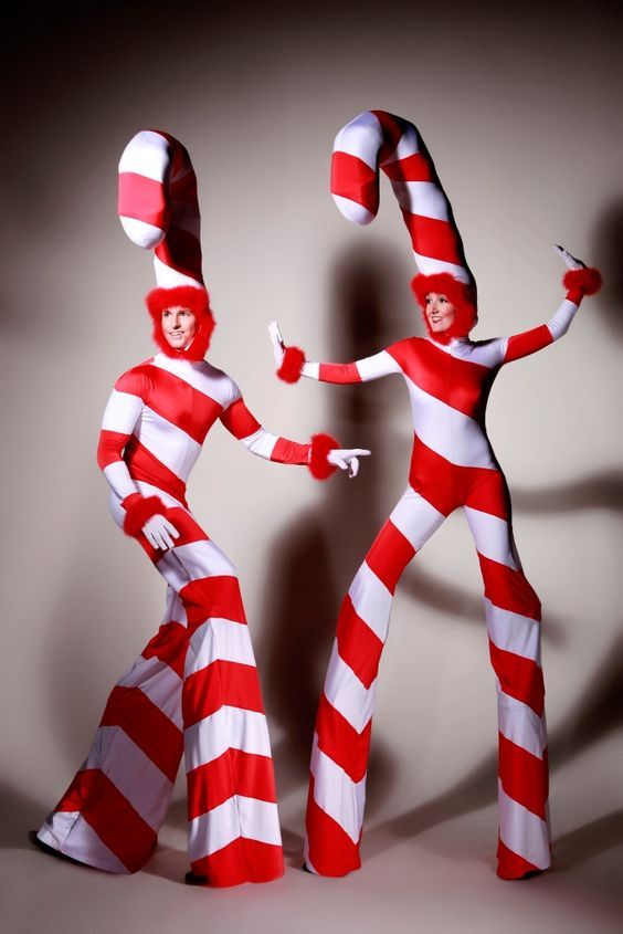 two people dressed in red and white striped costumes, one holding the other's hand