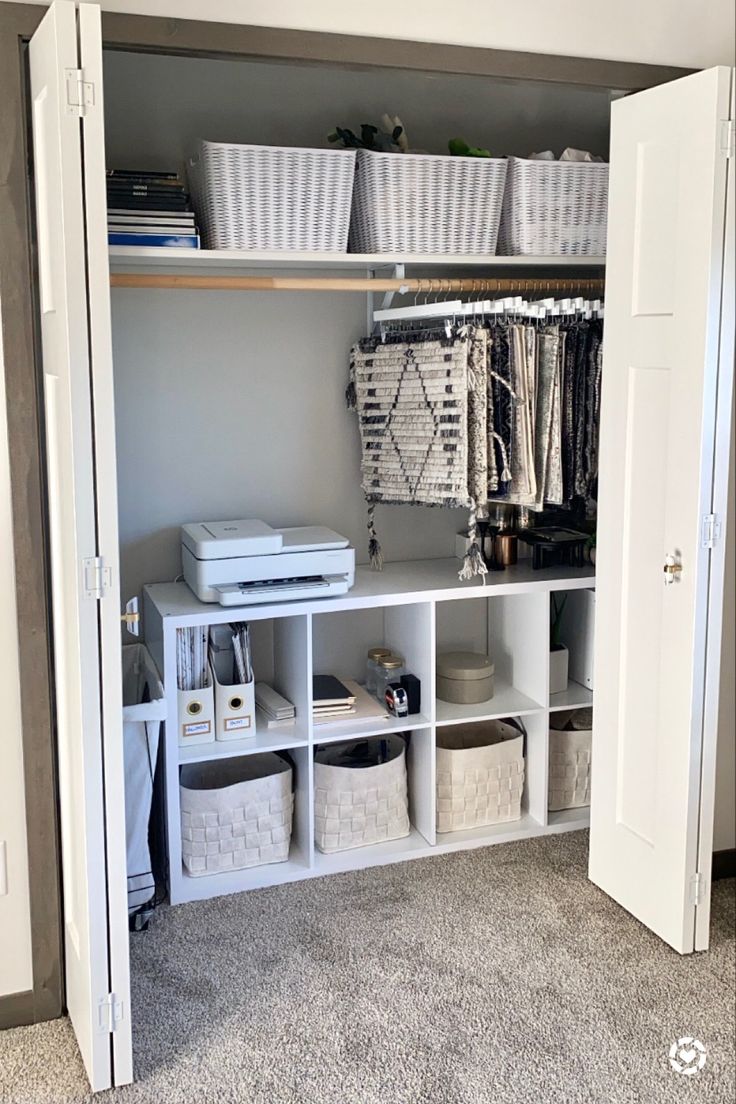 an organized closet with baskets, clothes and other items on shelves in the middle of it