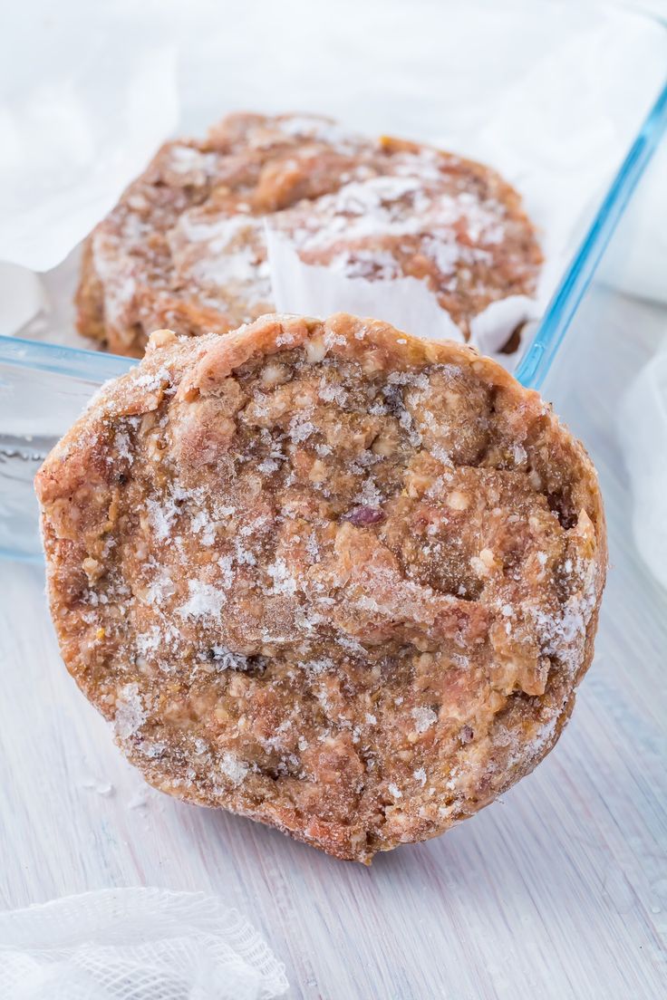 two cookies sitting on top of each other next to a plastic container filled with powdered sugar