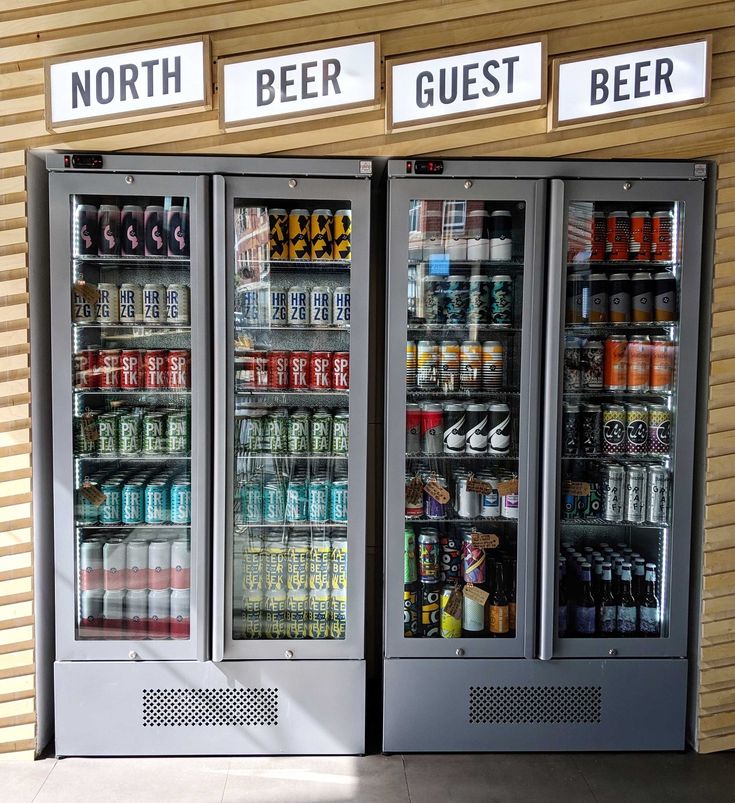 two coolers with drinks and beverages in front of a storefront display case that says north, beer, guest