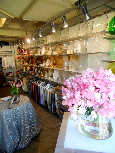 there is a vase with pink flowers on the table in front of plates and bowls