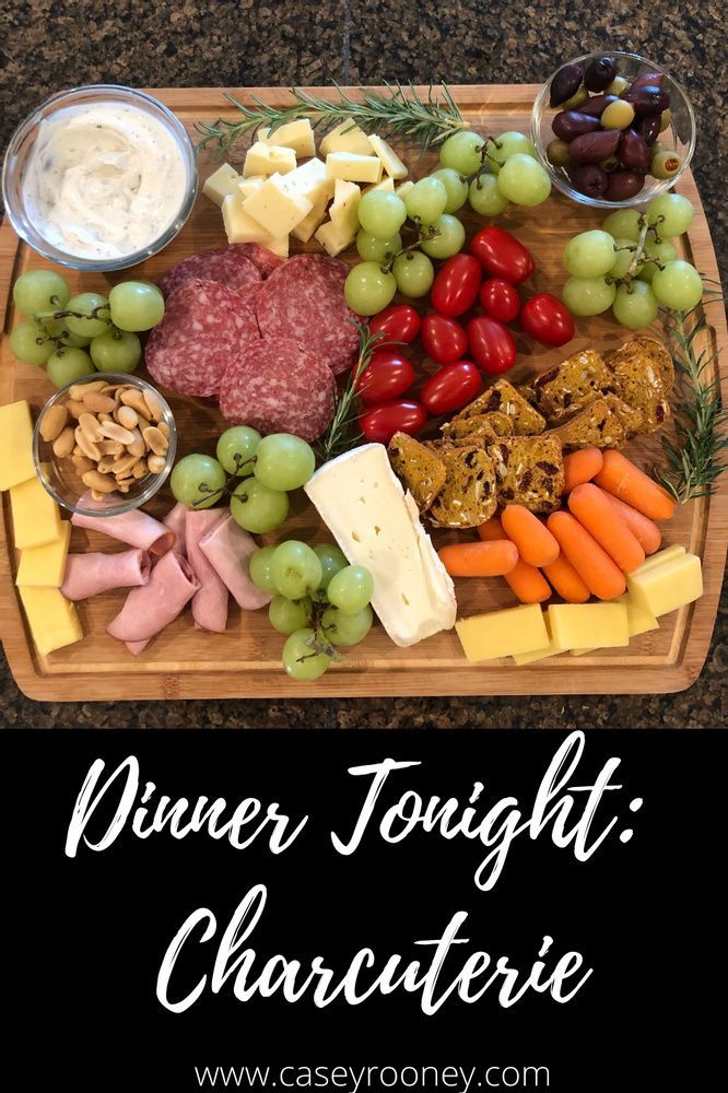 a cheese platter with grapes, meats, and vegetables on it is shown