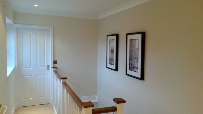 two framed pictures hang on the wall next to a stair case in an empty house