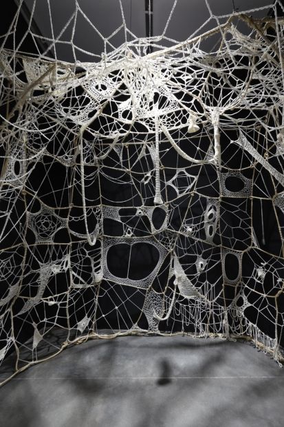 an artistic sculpture made out of wire and wood with holes in the center, surrounded by black background