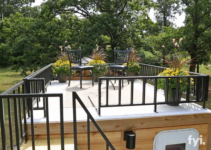 a dog house built into the side of a wooden deck with metal railings and planters