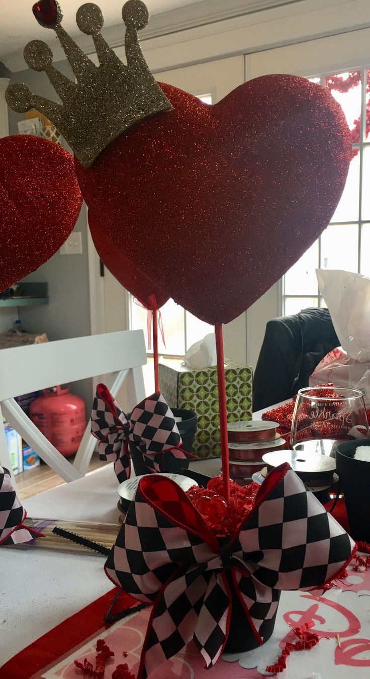 a table topped with red and black heart shaped balloons next to a couple of pictures