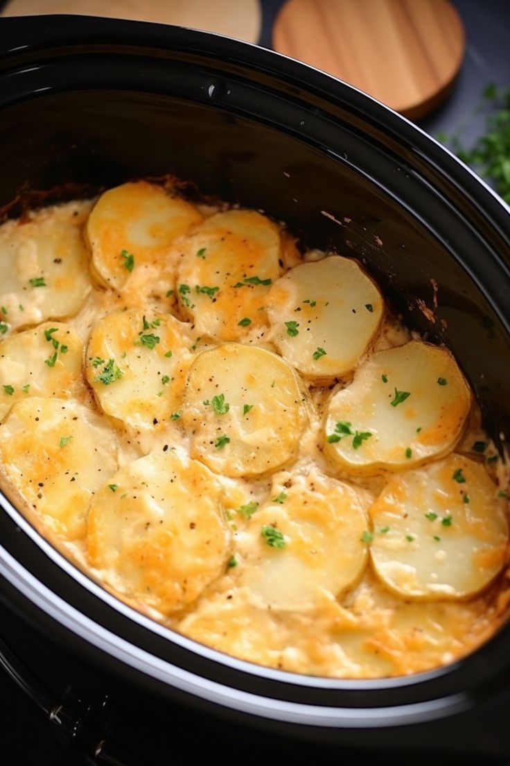 a crock pot filled with potatoes sitting on top of a table next to some parsley