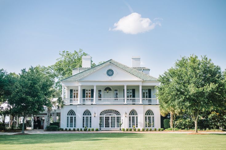 a large white house sitting on top of a lush green field