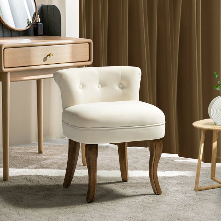 a white chair sitting in front of a mirror on top of a wooden dresser next to a table