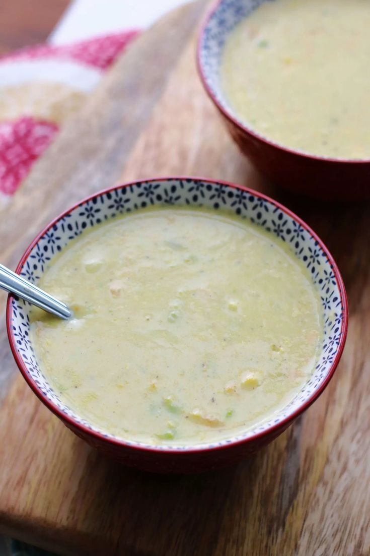 two bowls of soup sitting on top of a wooden cutting board next to each other