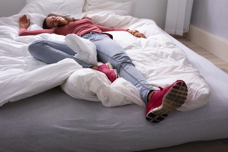 a woman laying on top of a bed covered in white sheets