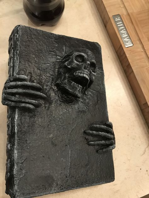 a black book sitting on top of a wooden table next to a bottle and knife