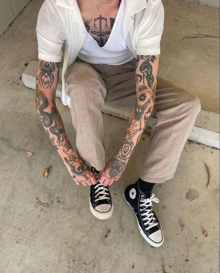 a man with tattoos sitting on the ground