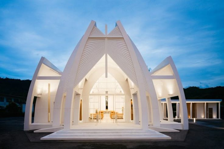 a large white church with an open front door at night, in the middle of a parking lot