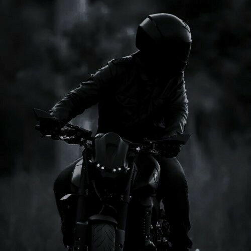 a man riding on the back of a motorcycle down a road in the dark night