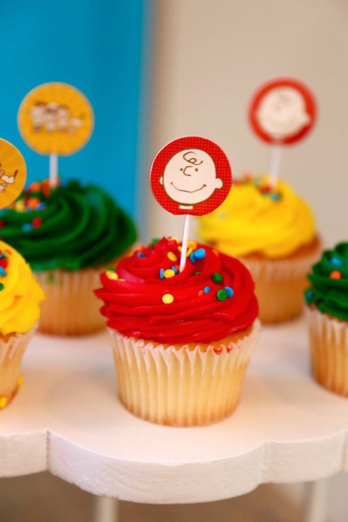 cupcakes with yellow frosting and red icing are on a white table