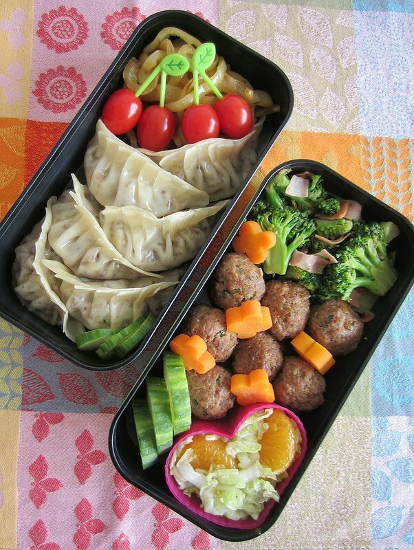 two black trays filled with food on top of a colorful tablecloth covered table