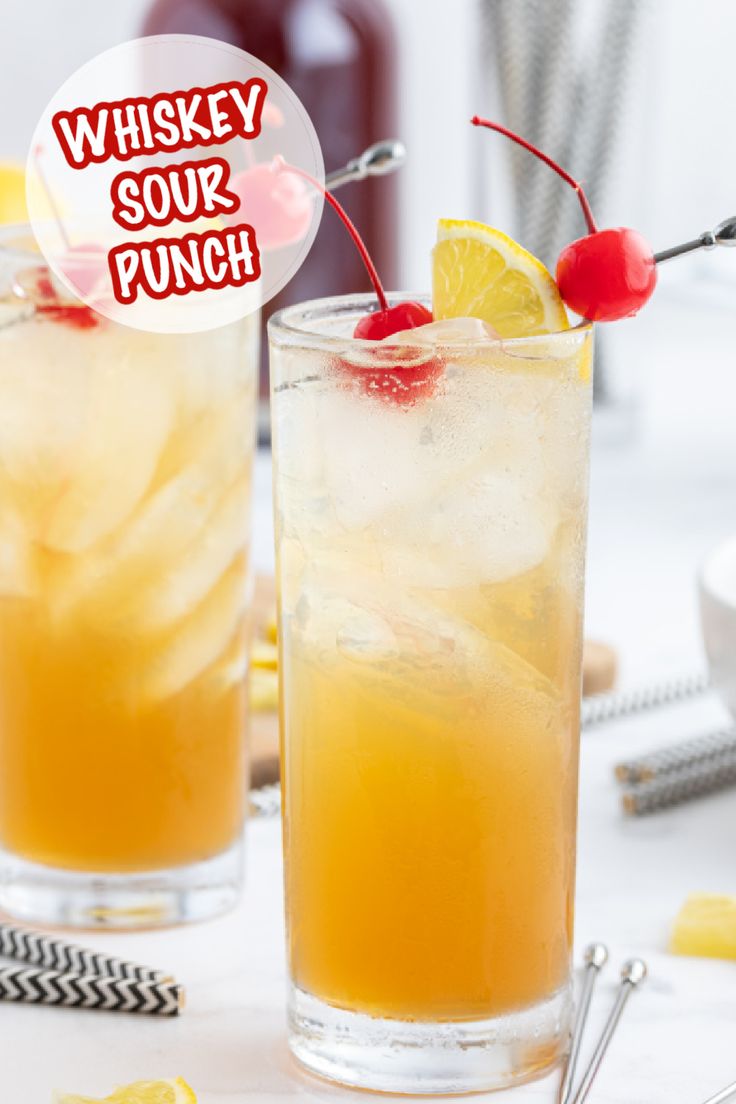 two glasses filled with lemonade and ice on top of a white table next to bottles