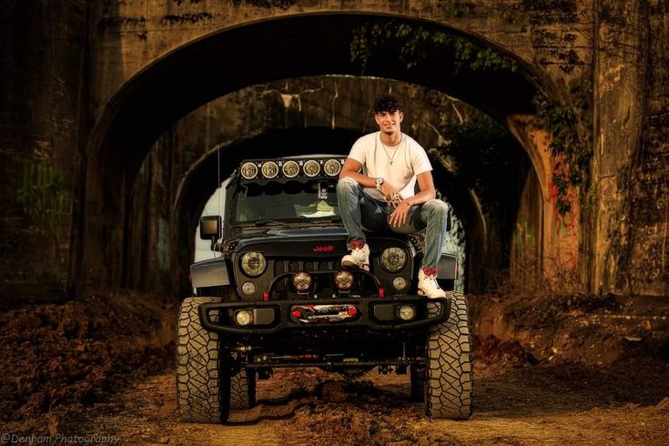 a man sitting on top of a jeep in the middle of a tunnel under a bridge