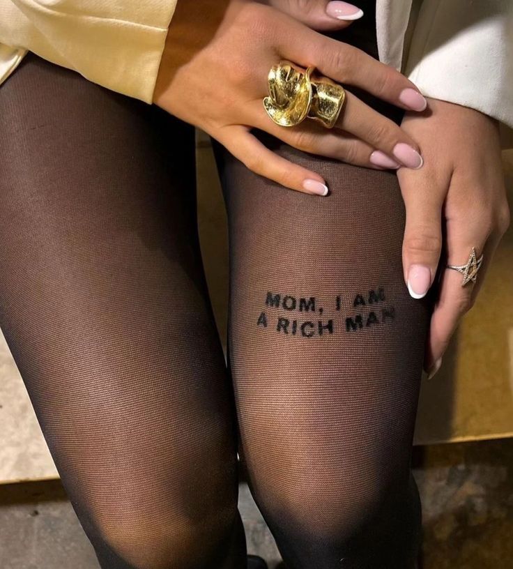 a woman wearing tights with words written on the side of her leg and gold ring