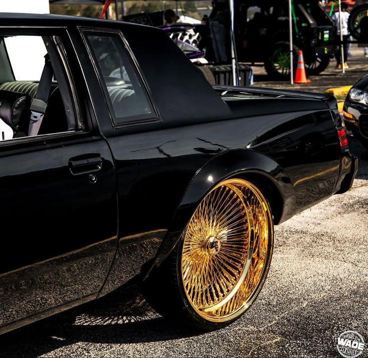 a black car with gold rims parked on the street