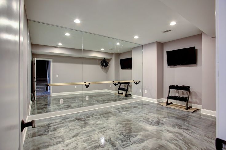 an empty room with grey marble flooring and mirrors on the wall, along with two black chairs