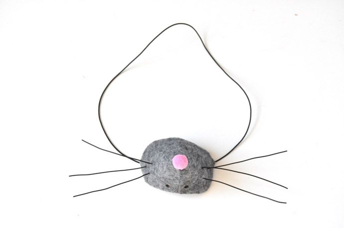 a mouse made out of felt sitting on top of a white surface with pink eyes