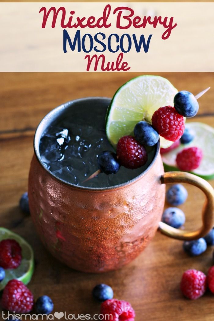 mixed berry moscow mule in a copper mug with limes and raspberries