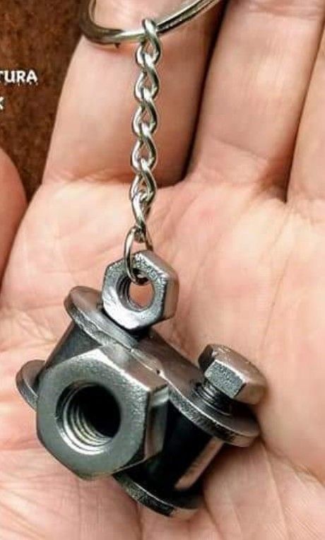 a hand holding a metal key chain with a nut on it's back end