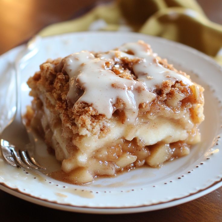 a slice of apple crumb cake on a white plate with a fork next to it