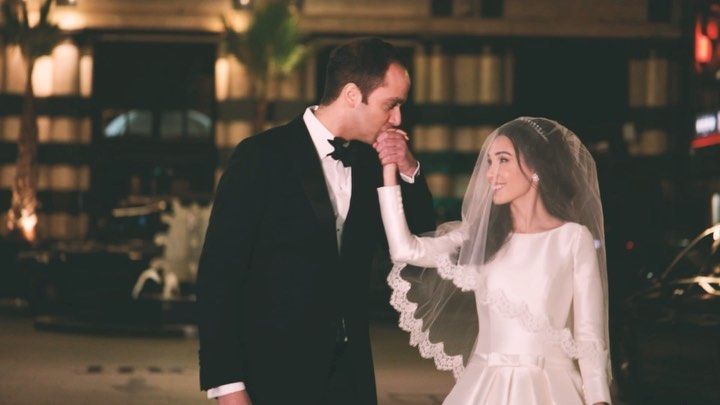 a bride and groom standing next to each other in front of a building at night