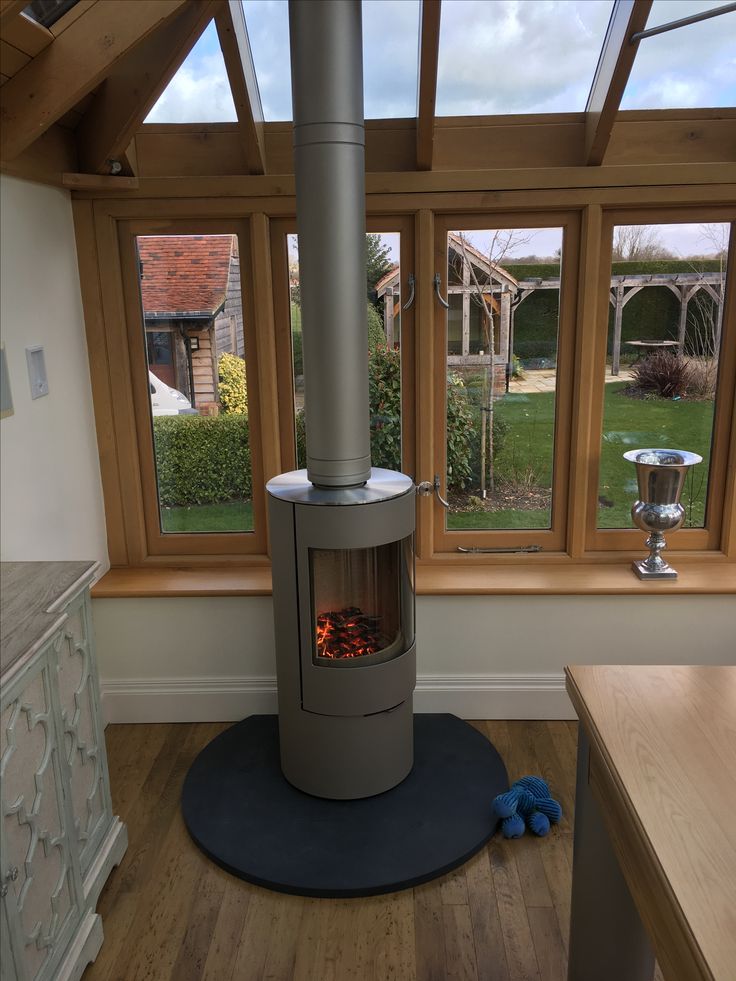 a stove sitting in the middle of a room next to a window with lots of windows