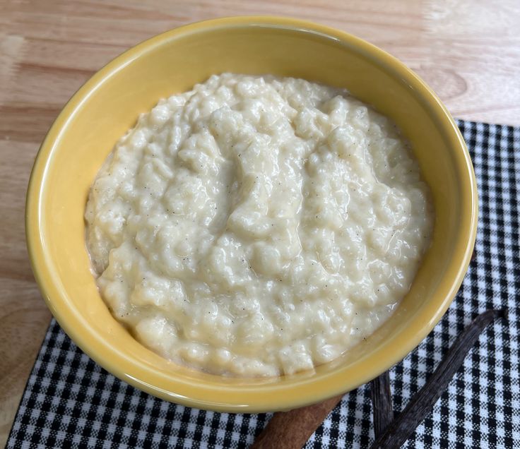 a yellow bowl filled with oatmeal on top of a checkered table cloth